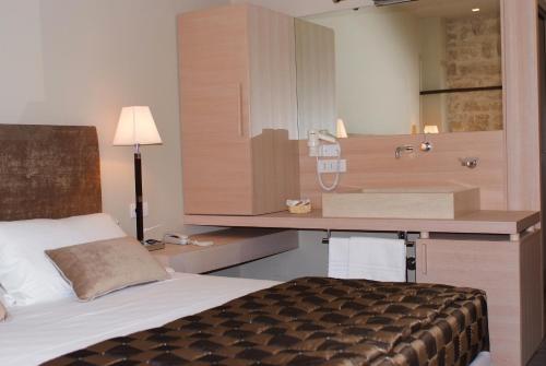 a bedroom with a bed and a desk with a sink at El Homs Palace Hotel in Comiso