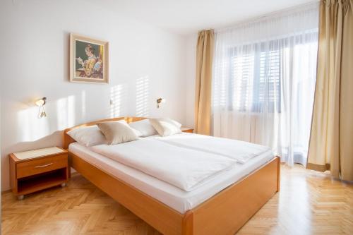 1 dormitorio con 1 cama grande con sábanas blancas y ventana en Bubi Apartments, en Malinska