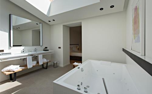 a bathroom with a tub and a sink and a mirror at Hotel Can Xiquet in Cantallops
