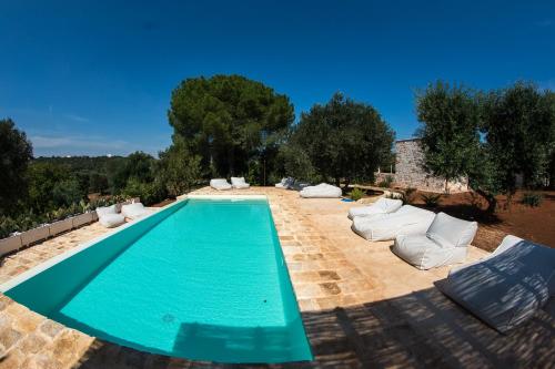 una piscina con sedie a sdraio bianche di Masseria Oreglia a Ceglie Messapica