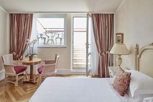 a hotel room with a bed and a table and chairs at Grand Hotel Timeo, A Belmond Hotel, Taormina in Taormina