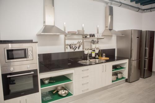 una cocina con armarios blancos y electrodomésticos de acero inoxidable en Vivian's Guest House, en Jerez de la Frontera