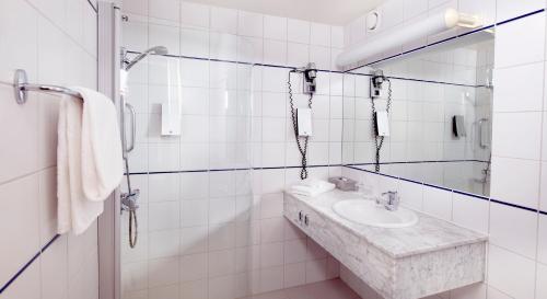 a white bathroom with a sink and a mirror at Home Hotel Arcticus in Harstad