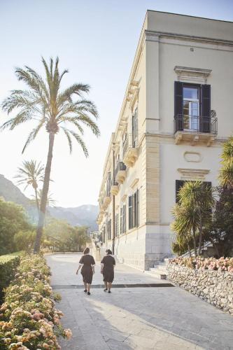 two people walking down a street next to a building at Grand Hotel Timeo, A Belmond Hotel, Taormina in Taormina