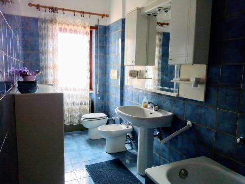 a blue tiled bathroom with a toilet and a sink at Da Marzia apartment in LʼAquila