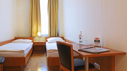 a hotel room with two beds and a desk with a laptop at Hotel Deutsches Haus in Kaub
