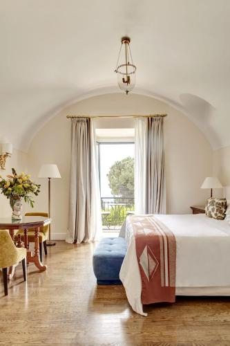 a bedroom with a bed and a table and a window at Grand Hotel Timeo, A Belmond Hotel, Taormina in Taormina