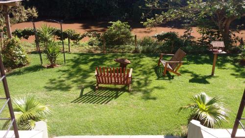 a yard with two chairs and a bird sitting on the grass at Hotel Santiago in Lindóia