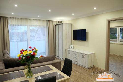 a living room with a couch and a table with flowers at Helios Apartamenty in Ustka