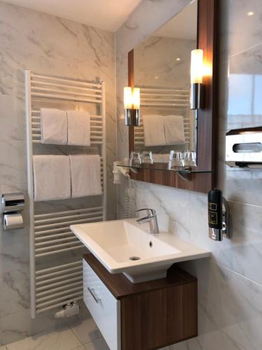 ein weißes Badezimmer mit einem Waschbecken und einem Spiegel in der Unterkunft Hotel König in Wien