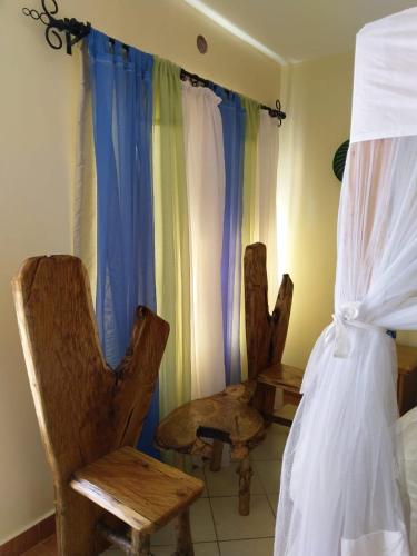 a bedroom with two chairs and a bed and curtains at Machakos Suites Luxury Hotel in Machakos
