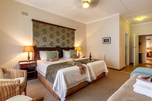 a bedroom with a large bed and two chairs at Porcupine Ridge Guest House in Sabie