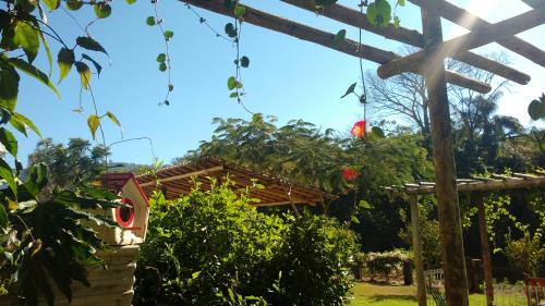 a garden with a wooden pergola and a bird house at Hotel Santiago in Lindóia