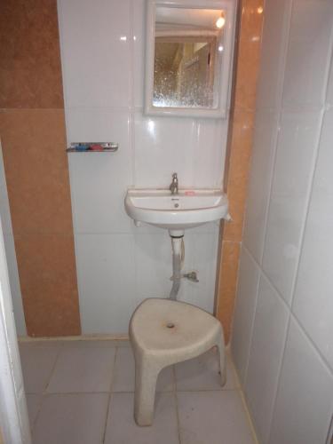 a small bathroom with a sink and a stool at HOTEL NEELKAMAL in Indore