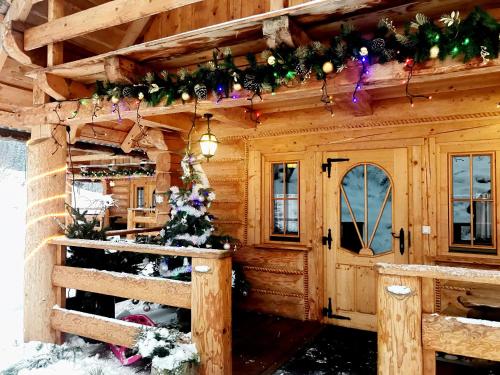 a log cabin decorated for christmas with a christmas tree at Leśniówka Domki W Karpaczu in Karpacz