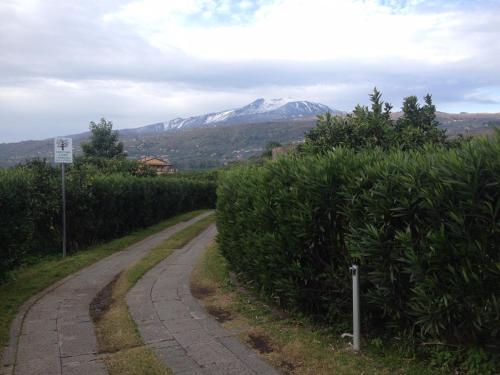 a winding road with a snow covered mountain in the distance at Feudogrande Bio Relais Hotel in Fiumefreddo di Sicilia