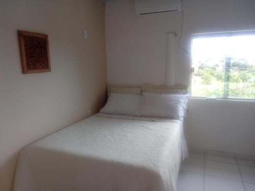 a small bedroom with a white bed with a window at Pousada Bela Vista de Mateiros in Mateiros