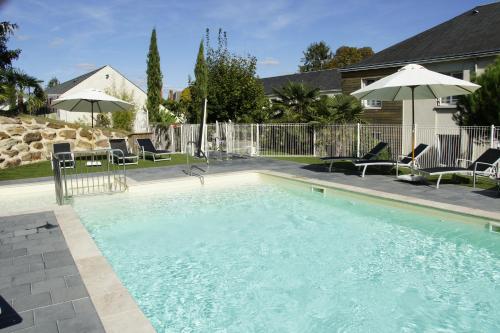 une grande piscine avec chaises et parasols dans l'établissement Les Hameaux de Beauval, à Saint-Aignan