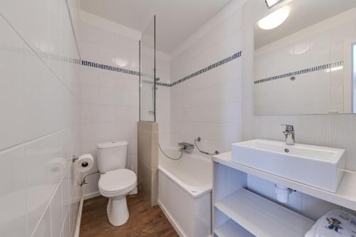 a white bathroom with a toilet and a sink at Holiday Suites De Haan in De Haan