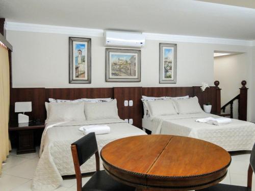 um quarto de hotel com duas camas e uma mesa de madeira em Hotel Real em Teófilo Otoni