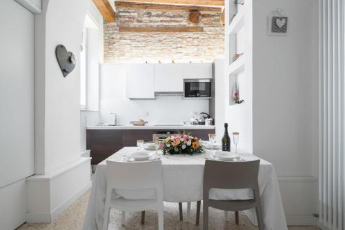 ein weißes Esszimmer mit einem weißen Tisch und Stühlen in der Unterkunft Ca' Flavia in Venedig