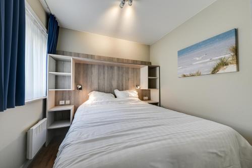 a bedroom with a large bed with a wooden headboard at Holiday Suites De Haan in De Haan