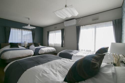 a room with four beds and two windows at villa yawaragi in Fujikawaguchiko