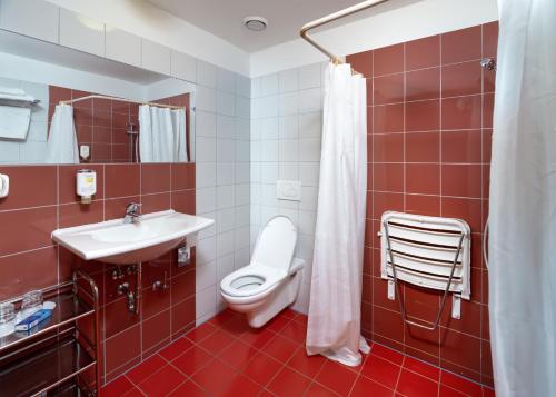 a red bathroom with a toilet and a sink at Hotel Chvalská Tvrz in Prague