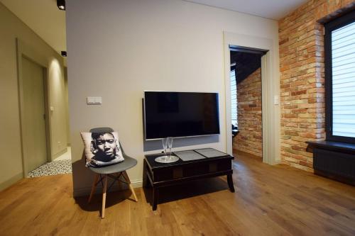 a living room with a tv and a chair at Jewish Quarter Comfort - In City Apartments in Krakow