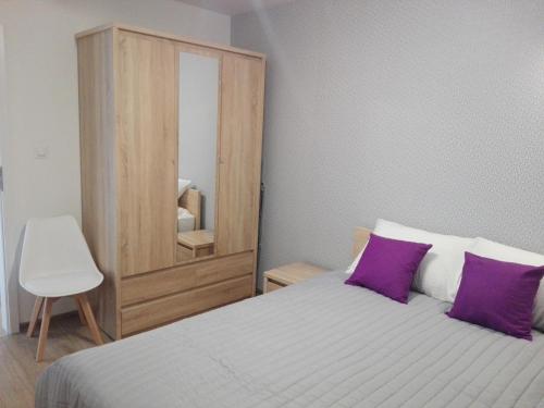 sypialnia z łóżkiem z fioletowymi poduszkami i lustrem w obiekcie Apartament Marzenie 5 - Opole w mieście Opole