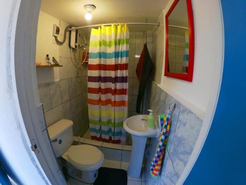a bathroom with a rainbow shower curtain and a sink at Urcia Surf House in Huanchaco