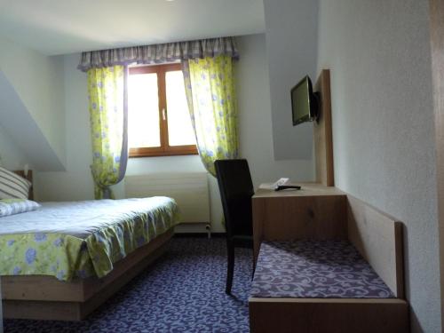 a bedroom with a bed and a desk and a window at Hotel Restaurant Le Petit Kohlberg in Lucelle