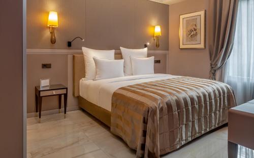 a hotel room with a bed with white pillows at Alàbriga Hotel GL in S'Agaro