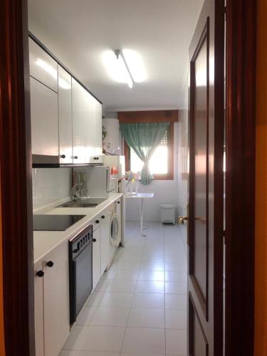 a kitchen with white cabinets and a sink and a stove at Rías Baixas in Baiona