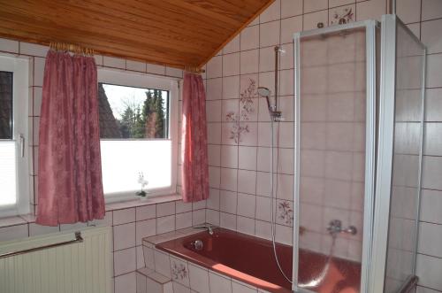 bagno con vasca rossa e finestra di Ferienwohnung Grensemann a Schneverdingen