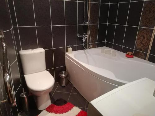 a bathroom with a white toilet and a bath tub at Justinos Apartamentai Panevėžyje in Panevėžys