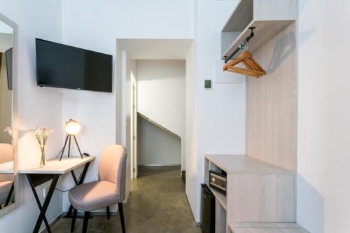 a room with a desk and a tv and a table and chairs at La Puerta de Palacio - Adults Only in Seville