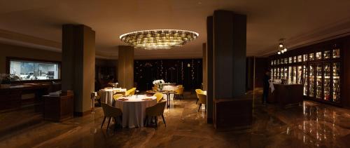 a dining room with tables and chairs and a chandelier at Alàbriga Hotel GL in S'Agaro