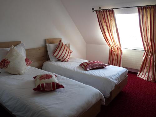 two beds in a hotel room with a window at Hotel Restaurant Le Petit Kohlberg in Lucelle