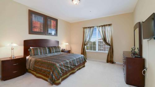 a bedroom with a bed and a flat screen tv at Chantilly Condo - closer to Disney and Universal in Orlando