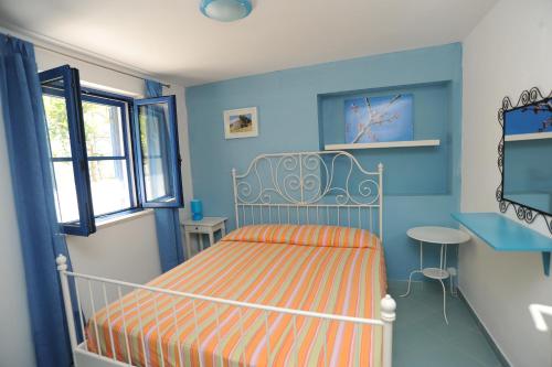 Dormitorio azul con cama y ventana en case vacanza montesaraceno, en Mattinata