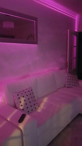 a living room with a white couch with pink lights at la CASITA DEL CORAZON in Castillo del Romeral