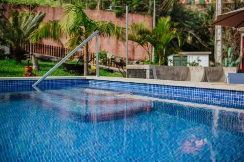 a blue swimming pool with an umbrella and trees at Villa Matta in Santana