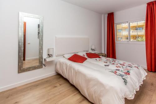 een slaapkamer met een bed met een spiegel en rode gordijnen bij Duplex Palm Mar C27 in Palm-mar