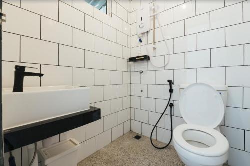 La salle de bains blanche est pourvue de toilettes et d'un lavabo. dans l'établissement A° HOTEL Semporna, à Semporna