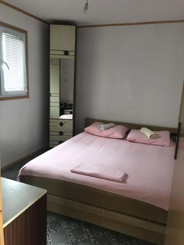 a bedroom with a bed with pink sheets and a mirror at Ada Bojana Apartmani in Gornji Štoj