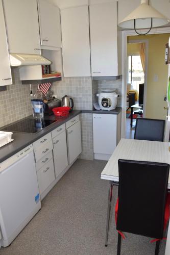 une cuisine avec des armoires blanches et une table avec des chaises dans l'établissement Rue Roland Garros, à Fréjus