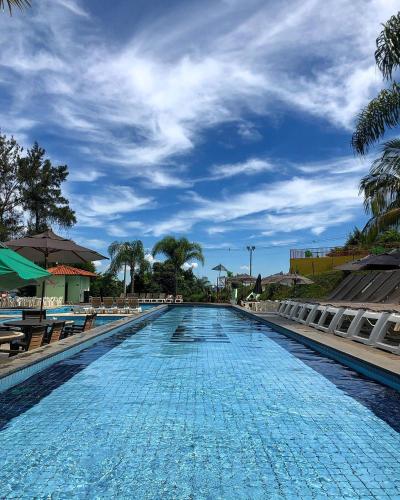 a swimming pool with a blue sky and palm trees at Tauá Hotel & Convention Caeté in Caeté