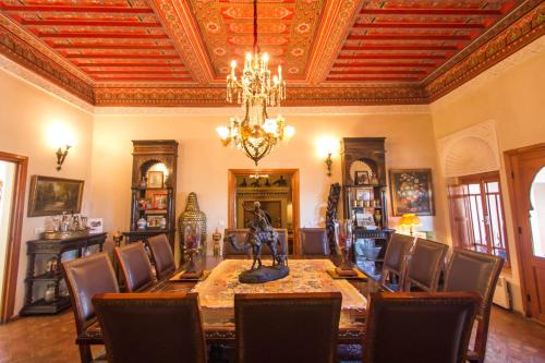 une salle à manger avec une table, des chaises et un lustre dans l'établissement Riad Thamayna, à Sale