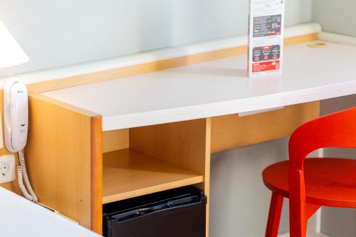 a desk in a room with a red chair at Ibis Elche in Elche